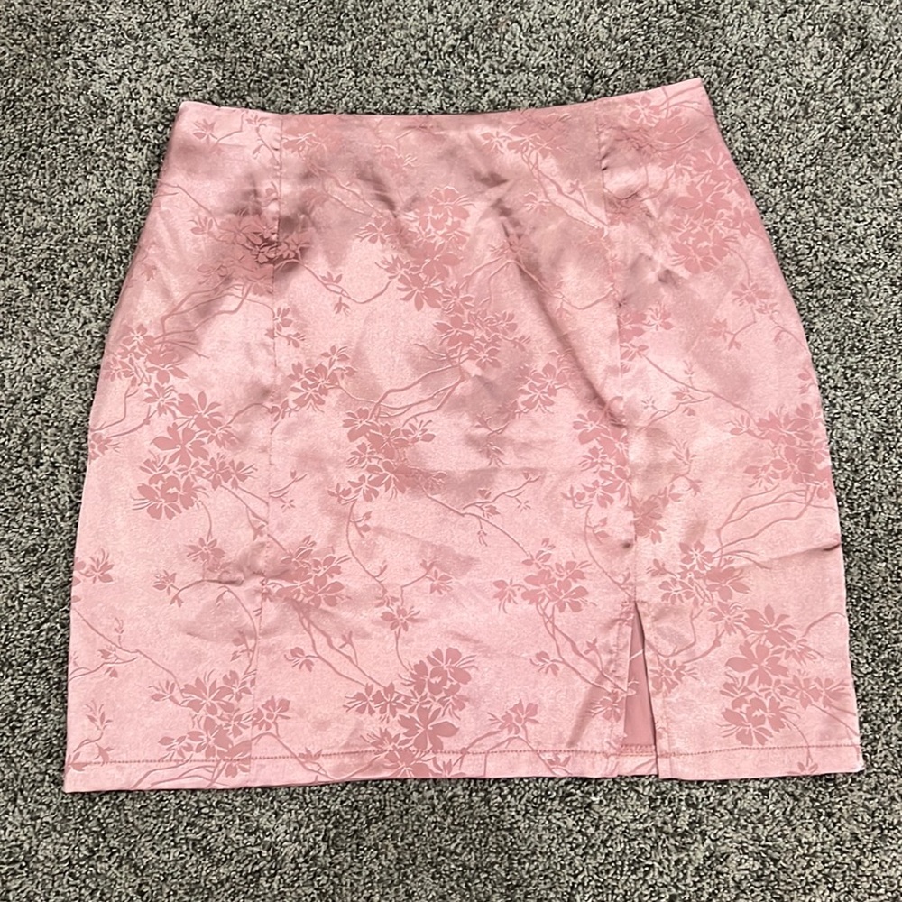 pink silk mini skirt with flower detailing and zipper on the back and a slit